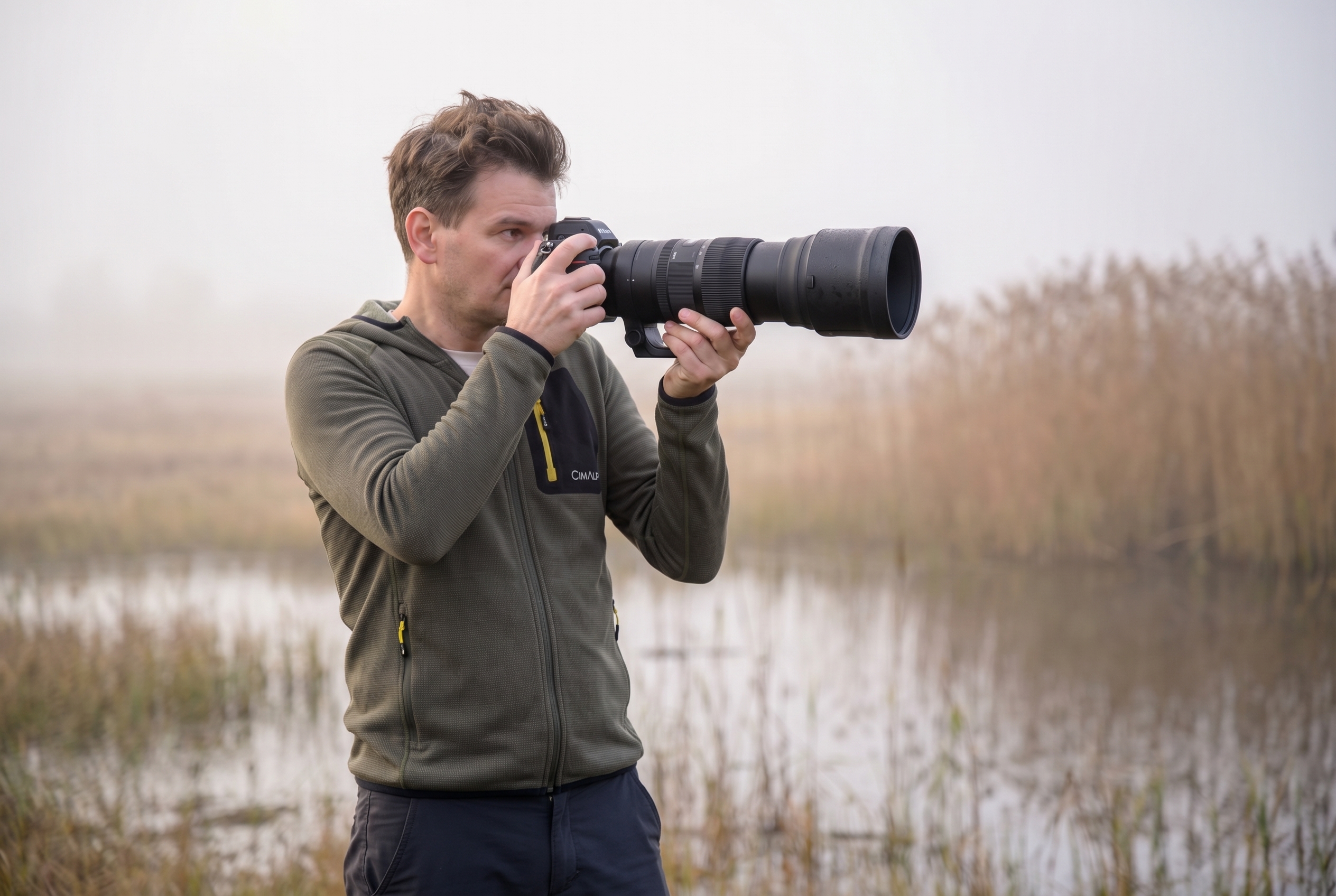 Photographe animalier débutant utilisant un téléobjectif Sigma 150-600mm dans un marais au lever du soleil pour apprendre la photo de nature.