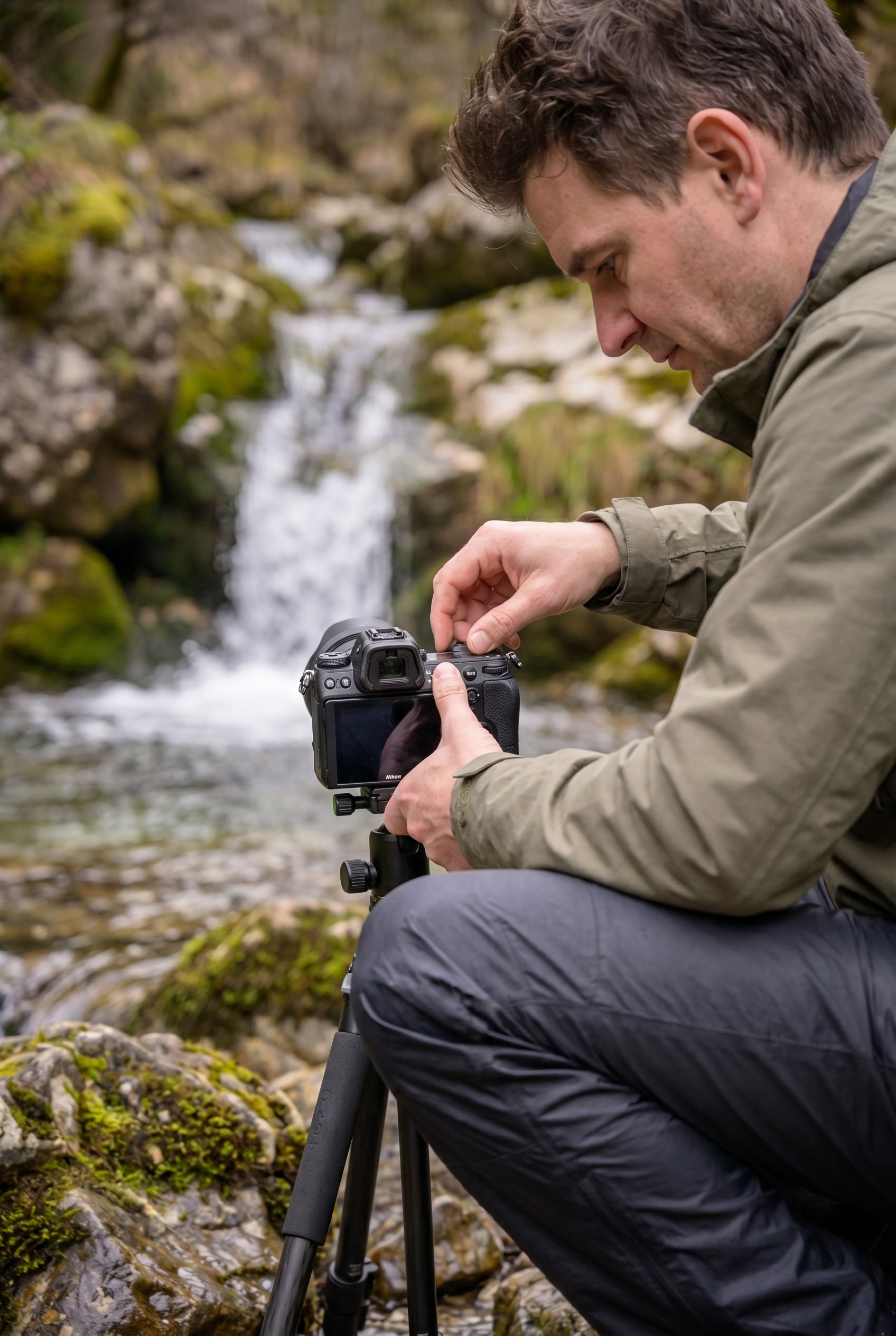 Photographe utilisant un trépied pour photographier une cascade et obtenir un effet d'eau soyeuse