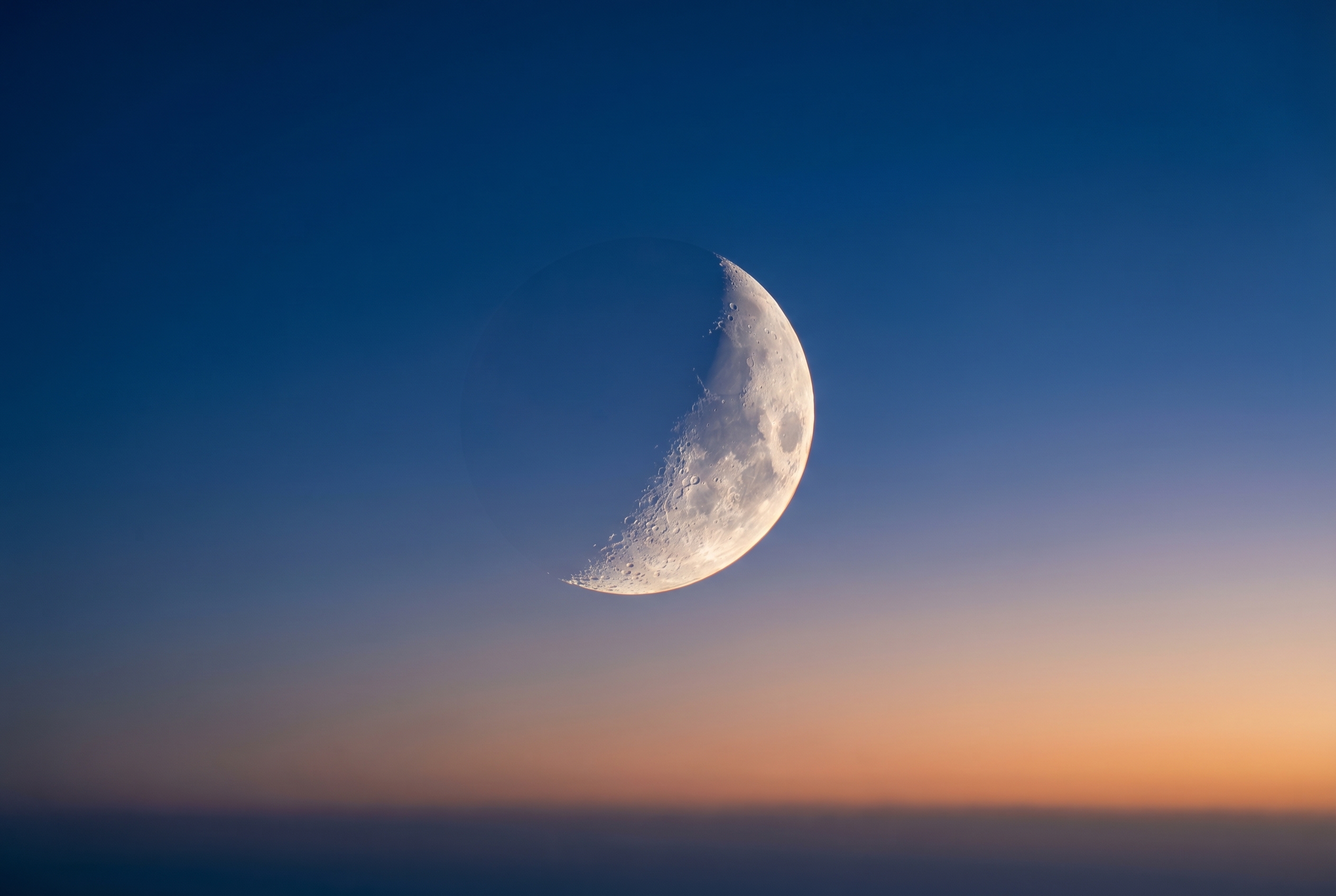 Photographie d'un croissant de lune net avec détails des cratères à l'heure bleue, illustrant comment photographier la lune avec précision.