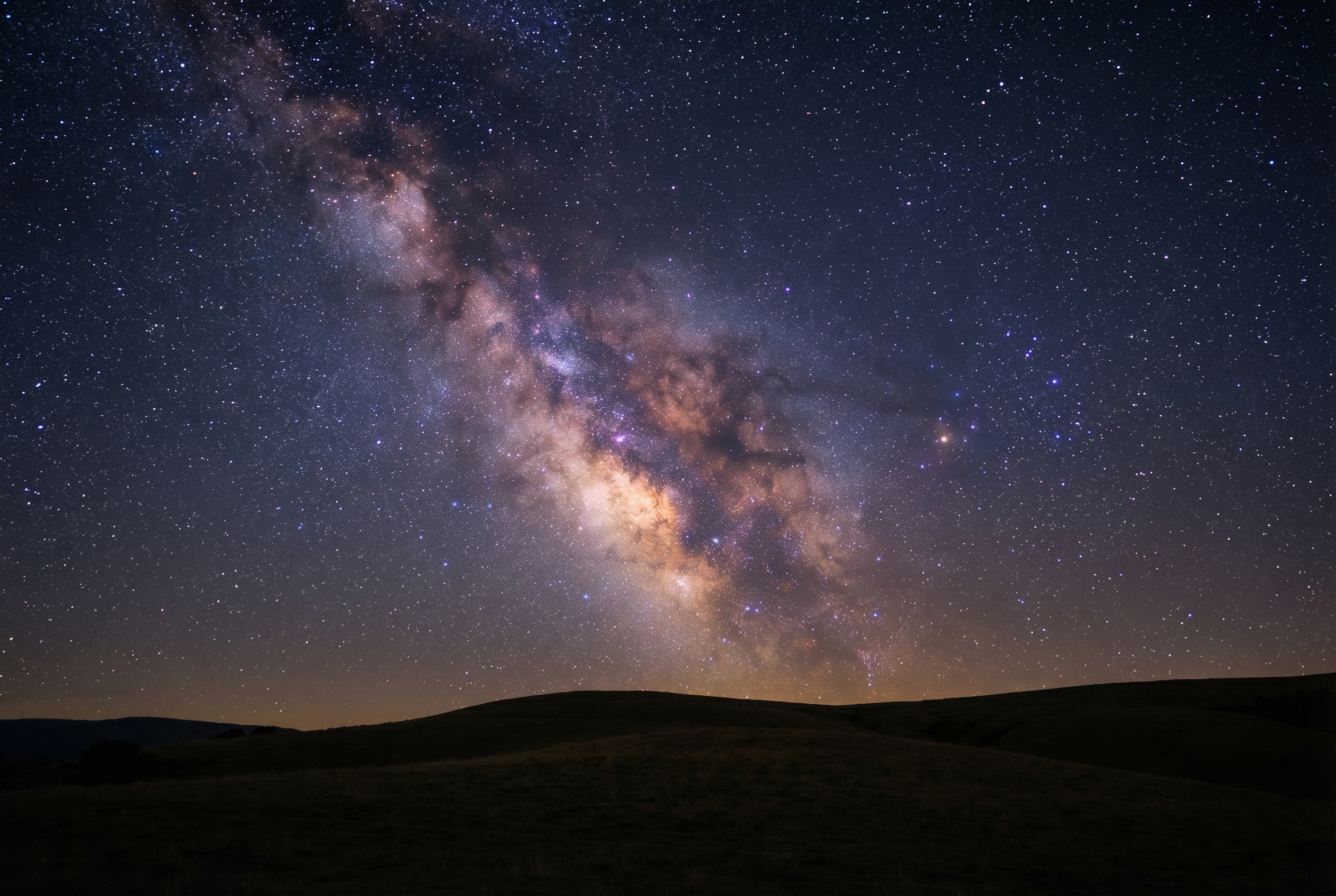 Astrophotographie du cœur de la Voie lactée s'élevant au-dessus d'un paysage de collines en France, illustrant parfaitement comment photographier la voie lactée.