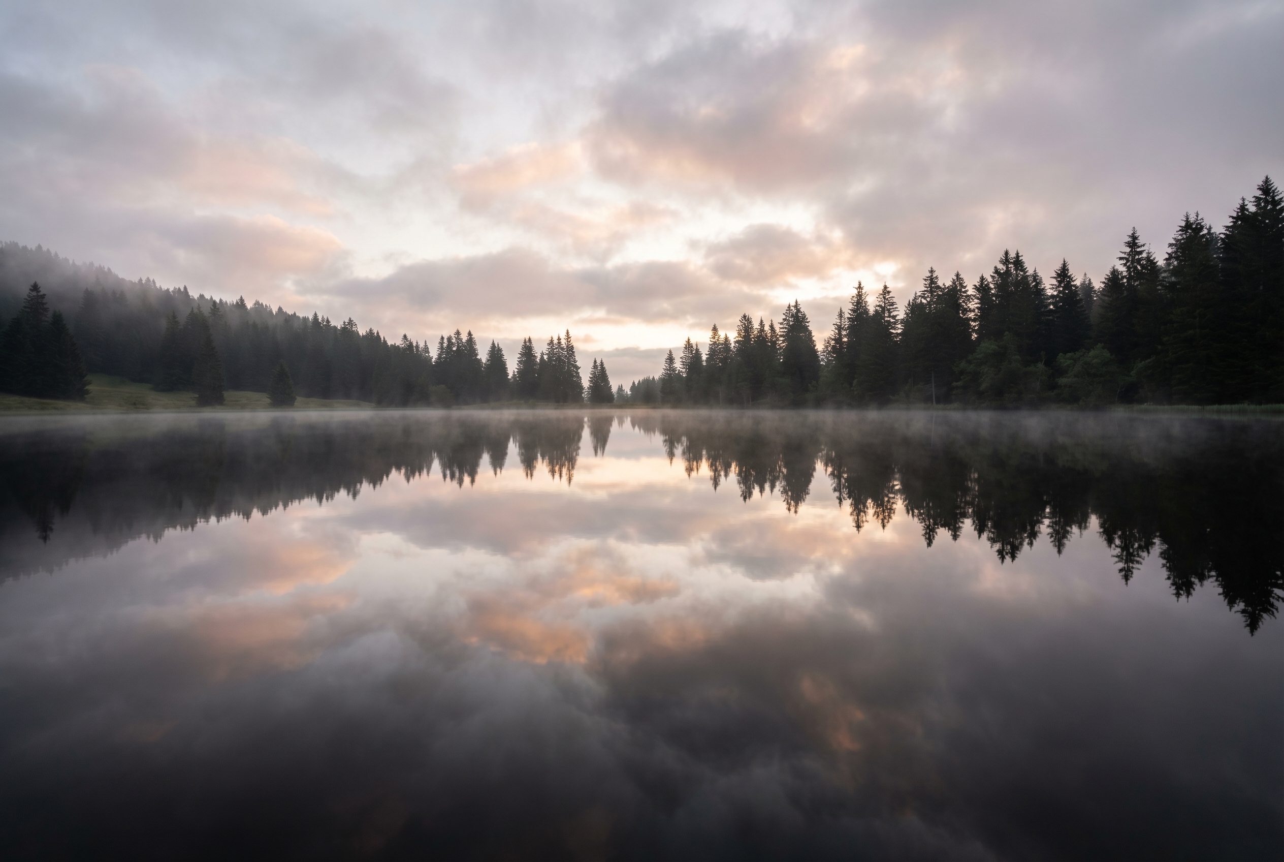 Photographie d'un lac des Alpes à l'aube avec une ligne d'horizon centrée pour illustrer les bases de la composition et la règle des tiers.