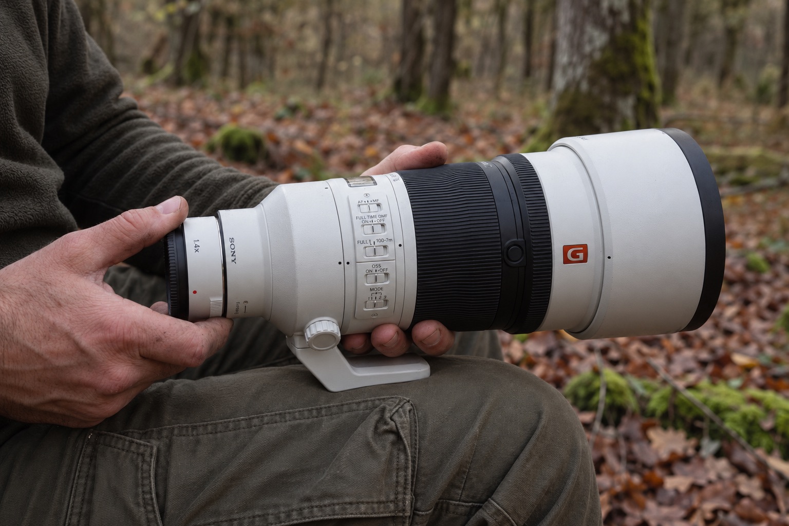 Test Sony FE 400mm f/4.5 GM OSS : avis et retour d'expérience terrain 20 Gros plan des mains d'un photographe montant un téléconvertisseur Sony SEL14TC sur l'objectif blanc Sony FE 400mm f/4.5 GM OSS en forêt.