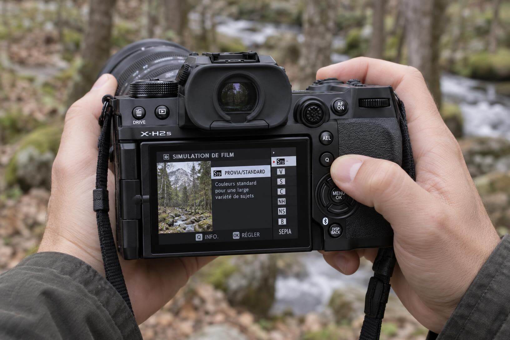 Prise en main du boîtier Fujifilm X-H2S lors d'un test terrain en forêt, montrant l'écran LCD arrière et le menu rapide (Q) pour la photo animalière.
